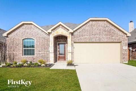 a brick house with a garage door and a lawn