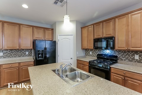 A kitchen with wooden cabinets and a black refrigerator.
