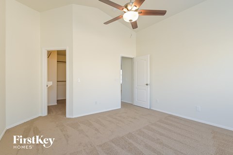 a spacious living room with carpet and a ceiling fan