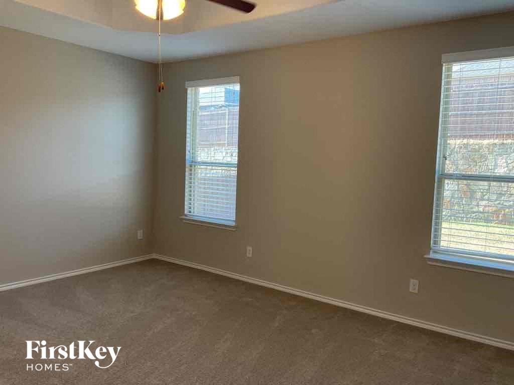 an empty bedroom with a ceiling fan and two windows