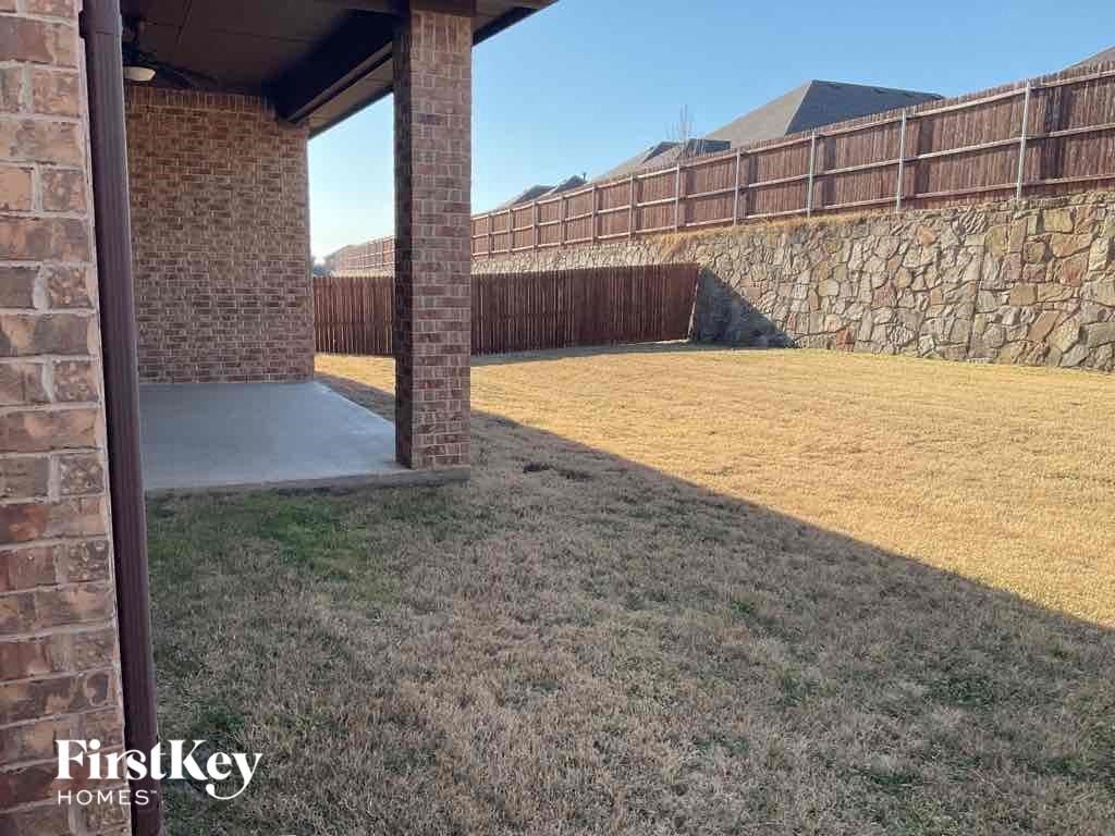 a backyard with a stone wall and a patio