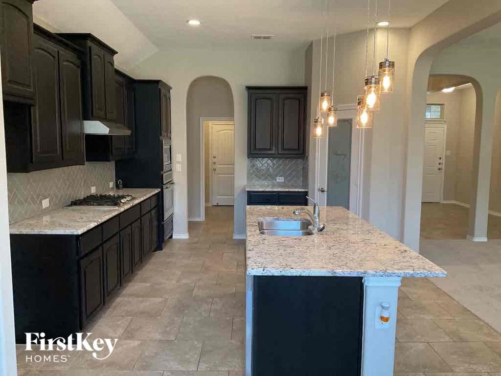 an open kitchen with black cabinets and marble counter tops