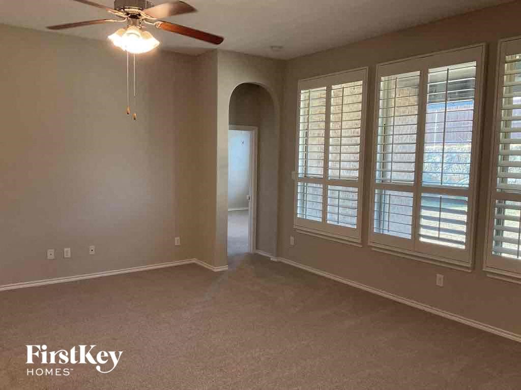 an empty living room with a ceiling fan and windows