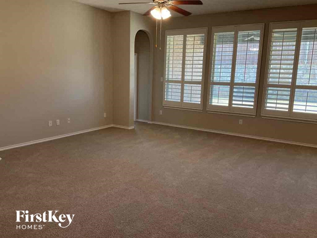 an empty living room with windows and a ceiling fan
