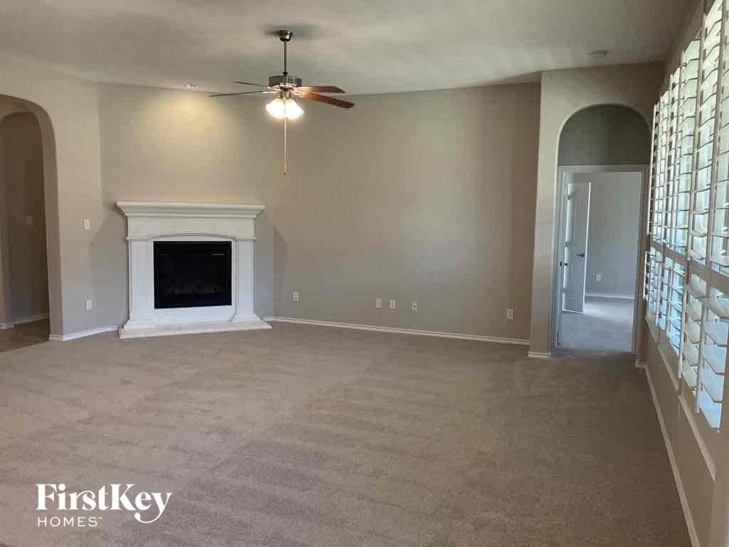 an empty living room with a fireplace and a ceiling fan