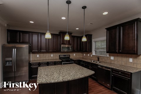 A kitchen with dark brown cabinets and a granite countertop.