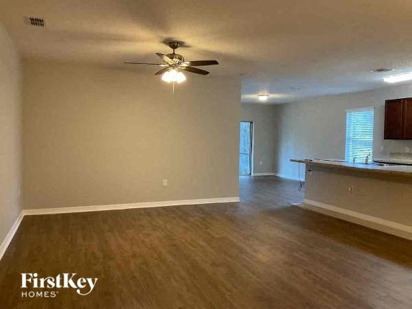 an empty living room and kitchen with a ceiling fan