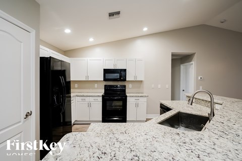 A kitchen with white cabinets and black appliances.