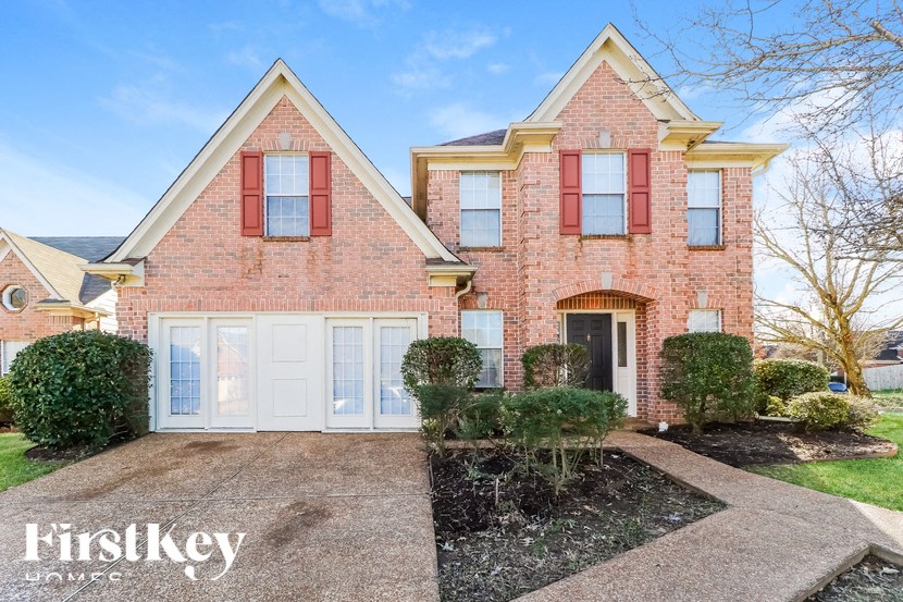 A brick house with a red and white front yard.