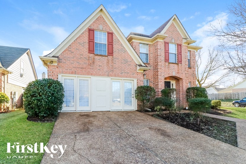 A brick house with a red roof and a white garage door.