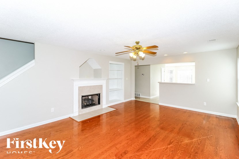 A spacious room with a fireplace and a ceiling fan.