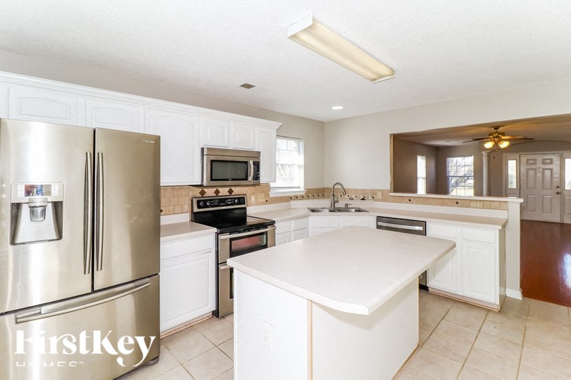 A kitchen with a refrigerator, microwave, oven, and sink.