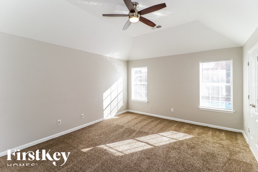 A spacious room with a carpeted floor and a ceiling fan.