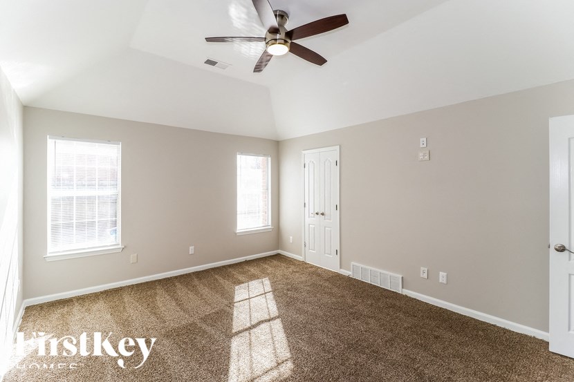 A spacious room with a ceiling fan and carpeted floor.