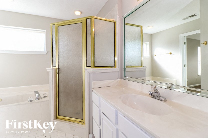 A bathroom with a white sink and a gold shower door.