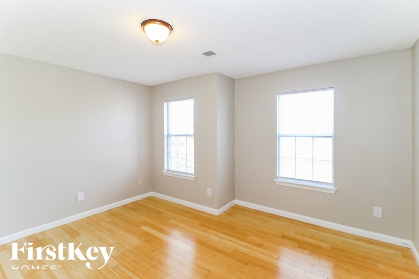 A room with wooden floors and two windows.