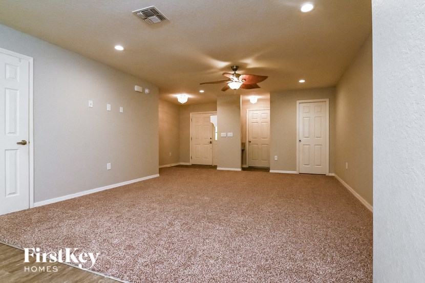 a spacious living room with carpet and a ceiling fan