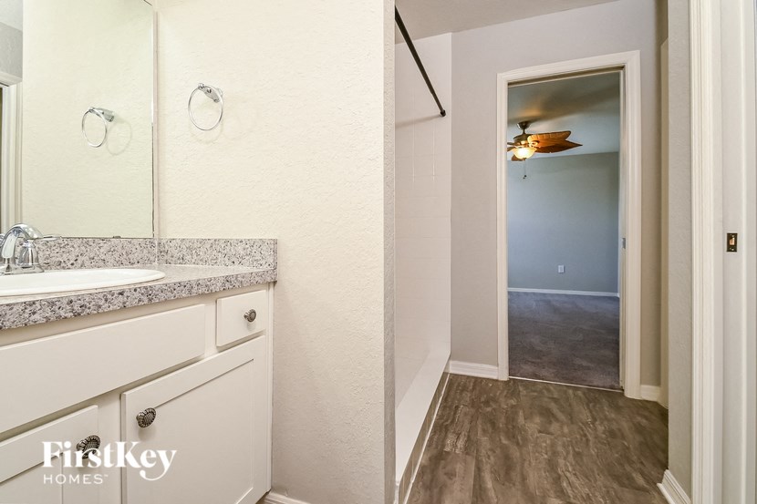 a bathroom with a sink and a mirror and a door to a hallway