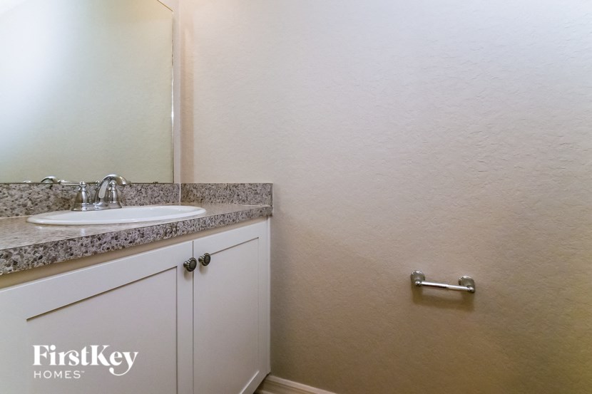 a bathroom with a sink and a mirror and a toilet paper dispenser