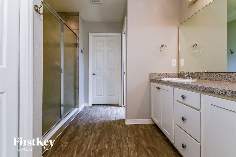 a bathroom with white cabinets and a shower and a sink