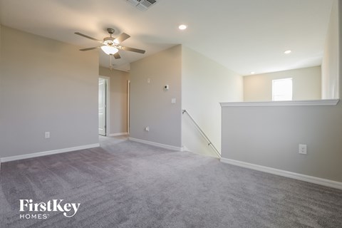 a living room with carpet and a ceiling fan