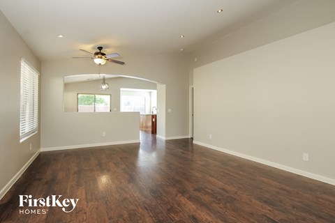 A spacious room with wooden floors and a ceiling fan.