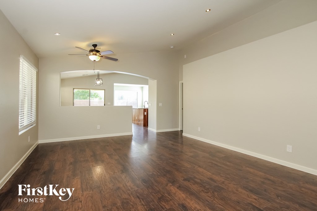 A spacious room with wooden floors and a ceiling fan.