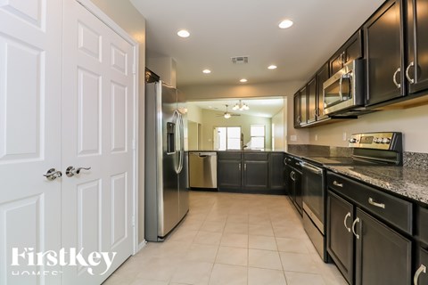 A kitchen with black cabinets and a white door.