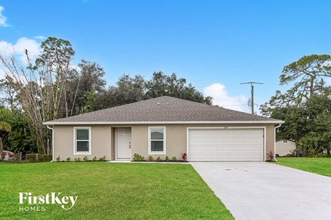 a beige house with a garage door and a lawn