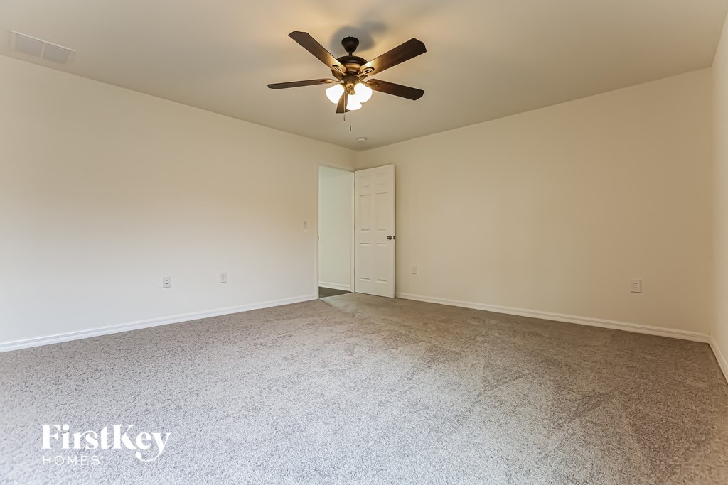 a spacious living room with carpet and a ceiling fan