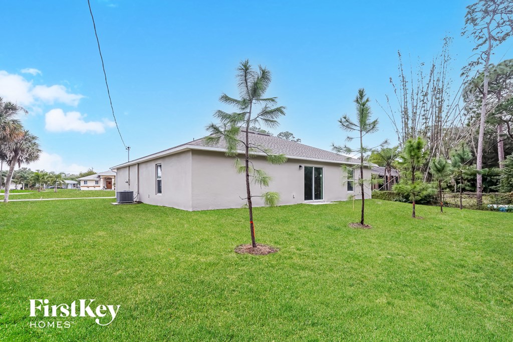 a home with palm trees in the yard and a white house