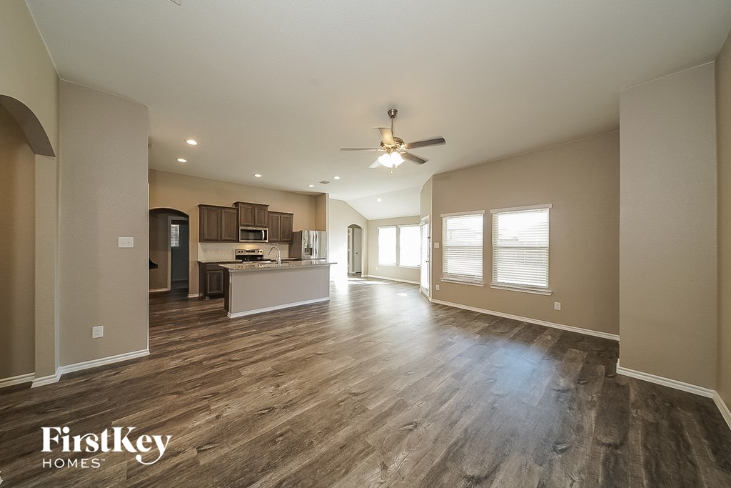 a living room and kitchen with wood floors and a ceiling fan