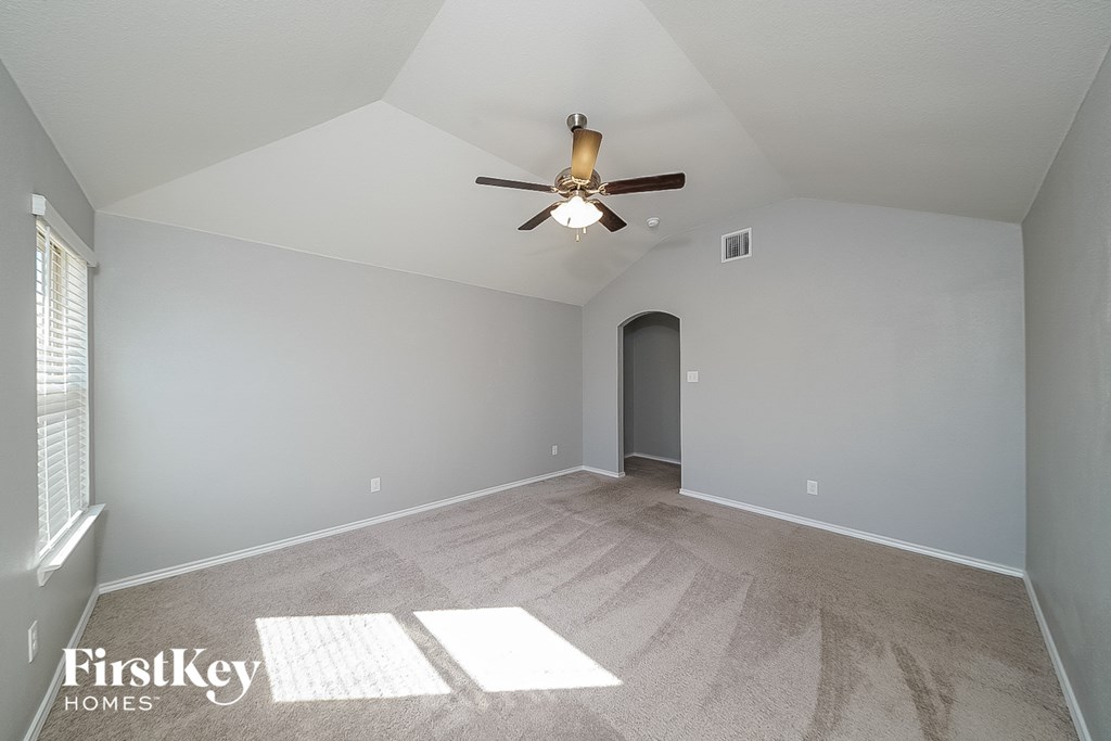 the spacious living room with ceiling fan and carpet