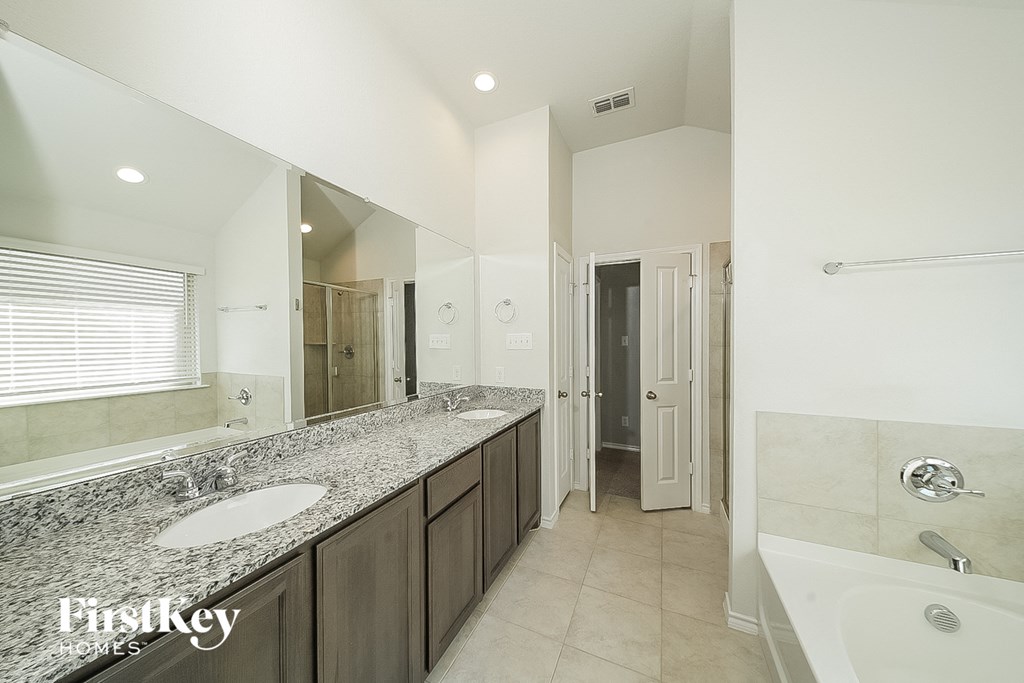 a bathroom with two sinks and a tub and a large mirror