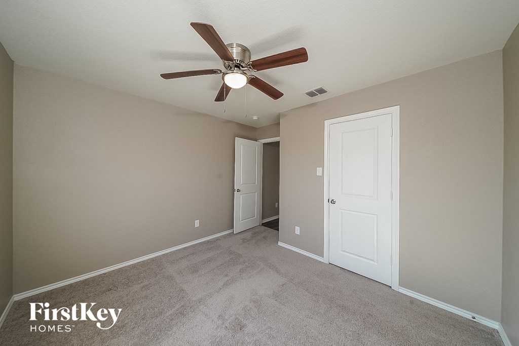 a bedroom with a ceiling fan and a door to a closet