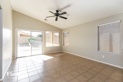 an empty living room with a ceiling fan and a sliding glass door