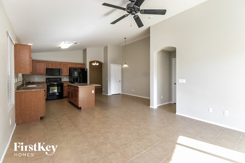 an empty kitchen and living room with a ceiling fan