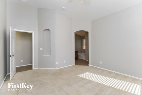 a master bedroom with a carpeted floor and a door to a bathroom