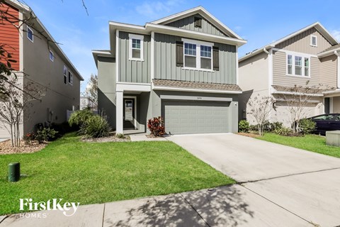 a green two story house with a garage and a lawn