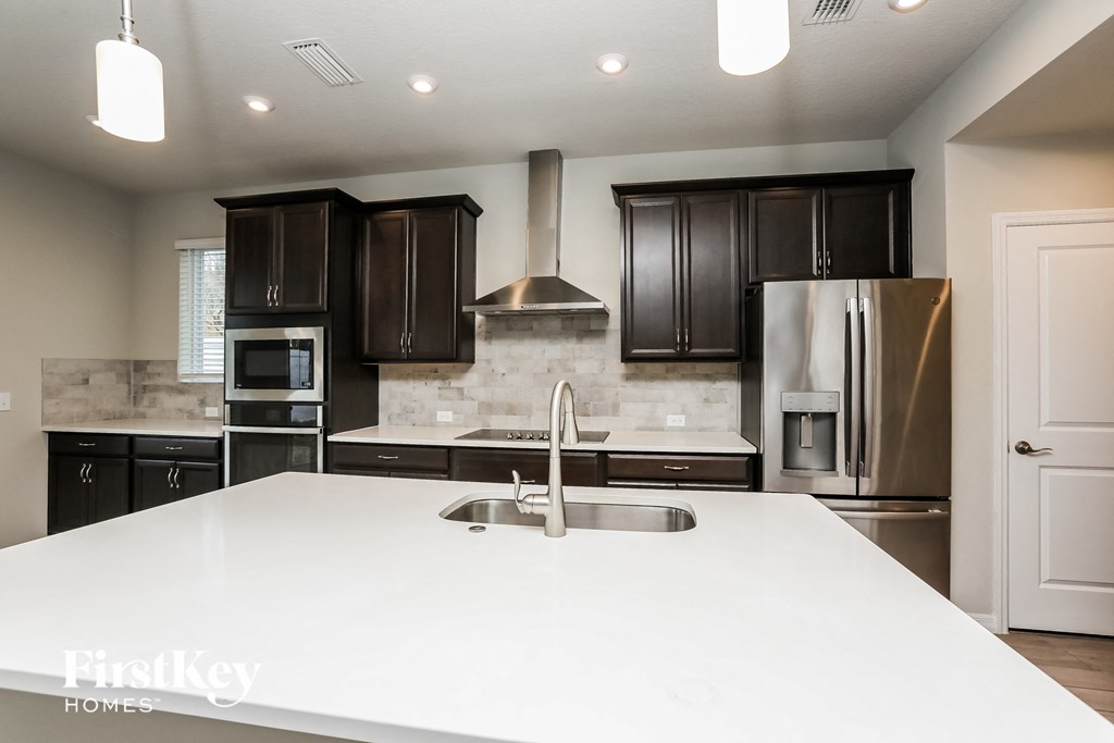 a large white kitchen with black cabinets and stainless steel appliances