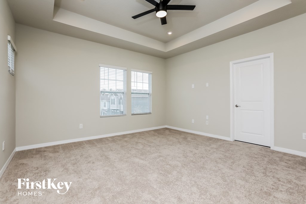 an empty living room with a ceiling fan and a window