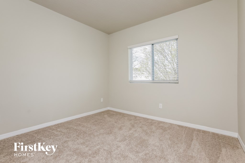 a bedroom with a window and a carpeted floor