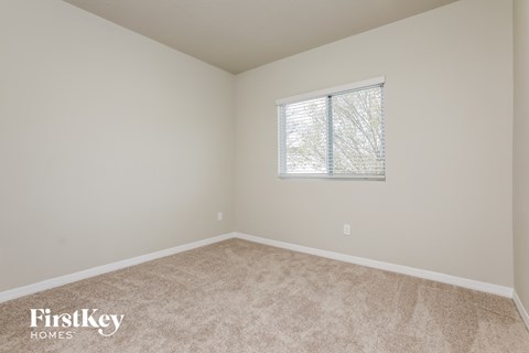 a bedroom with a window and a carpeted floor