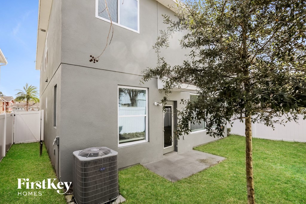 the backyard of a house with a tree and a trash can