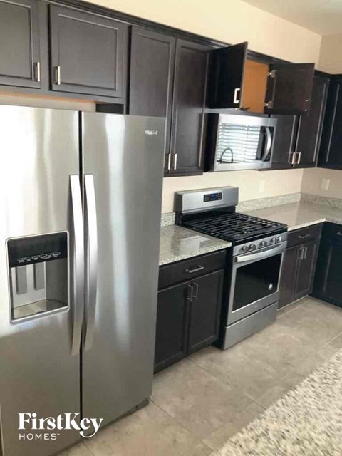 a kitchen with black cabinets and a stainless steel refrigerator