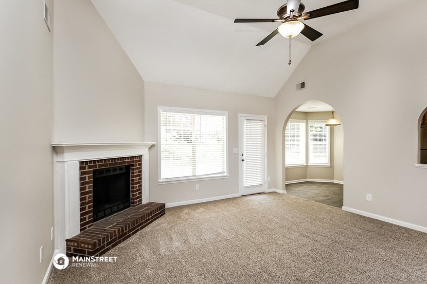 an empty living room with a fireplace and a ceiling fan