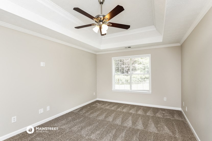 the living room of an empty home with a ceiling fan