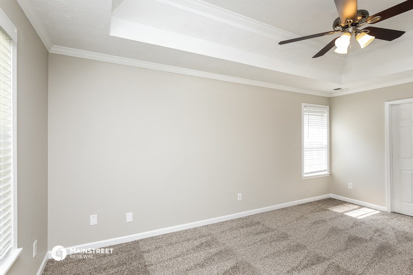 the spacious living room with ceiling fan and carpet