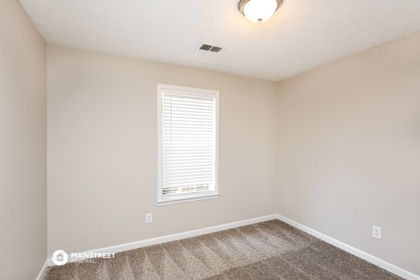 a bedroom with a window and a carpeted floor