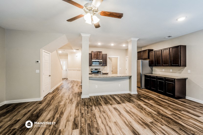 a living room with a kitchen and a ceiling fan